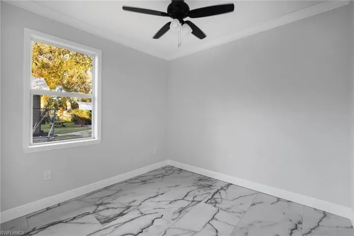 Unfurnished room featuring ceiling fan and ornamental molding
