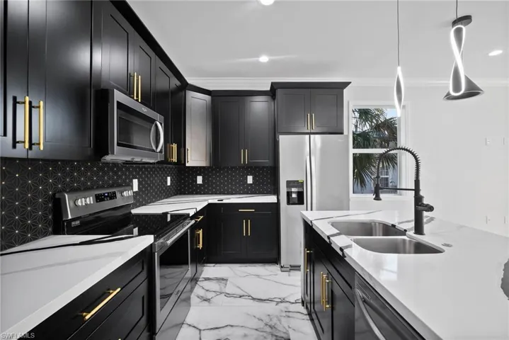 Kitchen featuring sink, hanging light fixtures, stainless steel appliances, tasteful backsplash, and ornamental molding