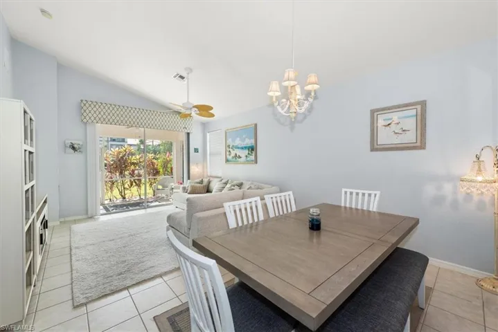 Dining room featuring lofted ceiling, ceiling fan, light tile patterned flooring, and a chandelier