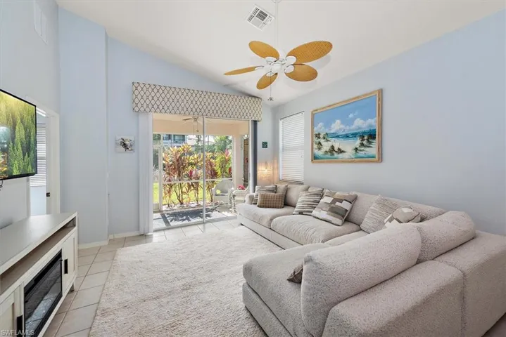 Living area featuring vaulted ceiling, a ceiling fan, and light tile patterned flooring
