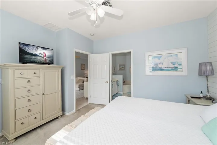 Bedroom with light colored carpet, ceiling fan, and ensuite bath