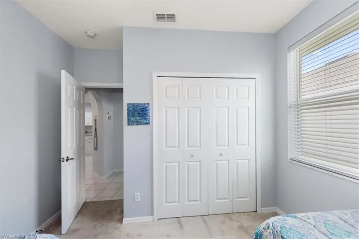 Bedroom with arched walkways, light carpet, and a closet