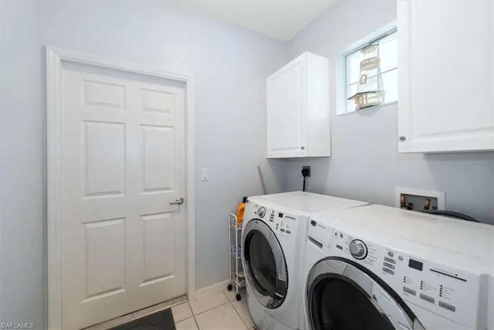 Laundry area featuring cabinet space, light tile patterned floors, and separate washer and dryer