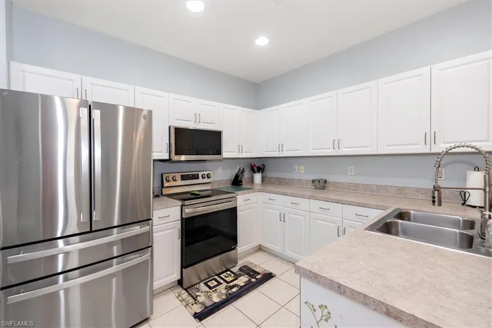 Kitchen featuring stainless steel appliances, white cabinets, light countertops, light tile patterned floors, and recessed lighting