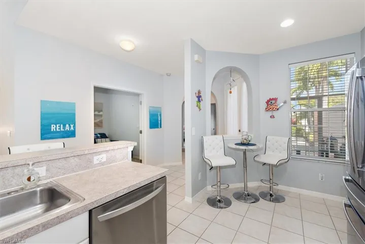 Kitchen featuring appliances with stainless steel finishes, light countertops, light tile patterned floors, recessed lighting, and arched walkways