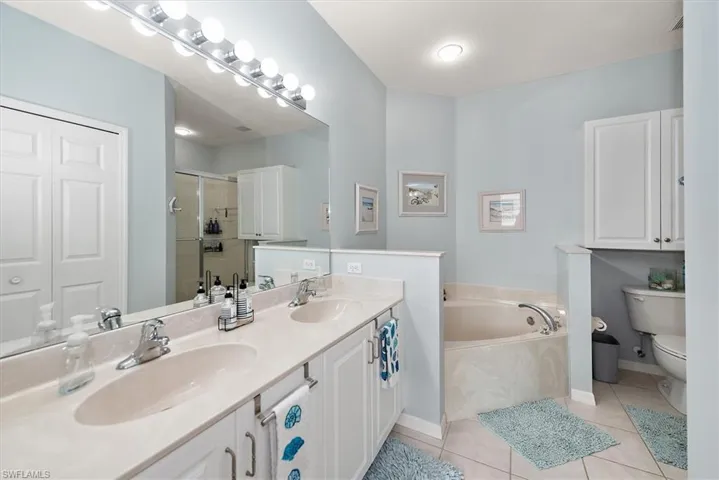 Bathroom with a shower stall, double vanity, light tile patterned flooring, a bath, and a closet