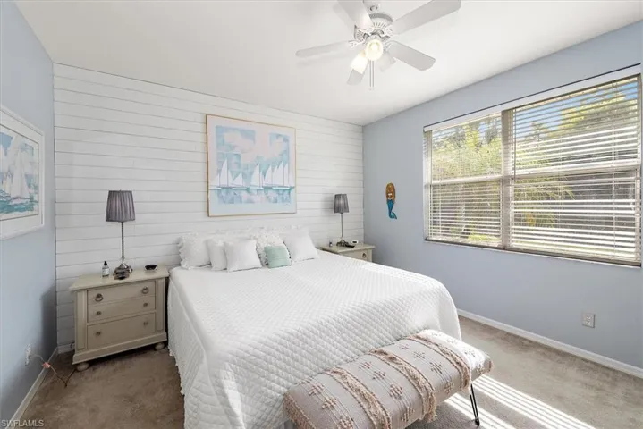 Carpeted bedroom with shiplap wall, an accent wall, and ceiling fan