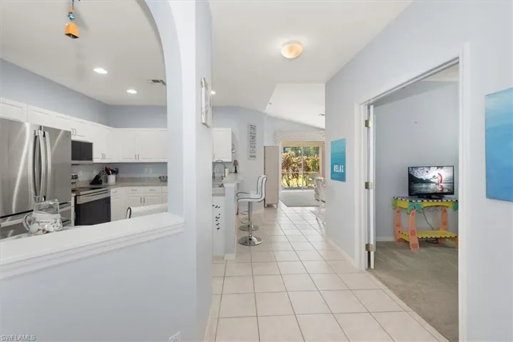 Hall featuring light tile patterned floors , and lofted ceiling