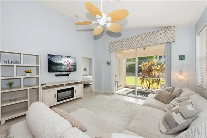 Living room with light tile patterned floors, vaulted ceiling, and a fireplace
