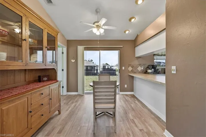 Dining area with baseboards, vaulted ceiling, ceiling fan, and light wood-type flooring