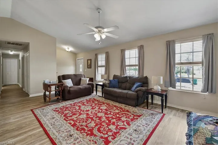 Living room featuring a ceiling fan, light wood look finished floors, vaulted ceiling