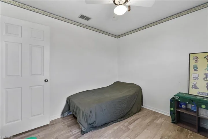 Bedroom with baseboards, visible vents, a ceiling fan, and wood look finished floors