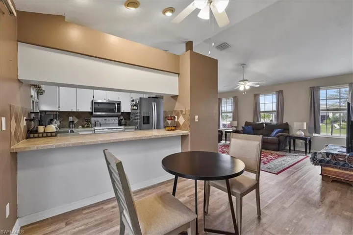 Kitchen featuring a peninsula, light wood-style flooring, a ceiling fan, and appliances with stainless steel finishes