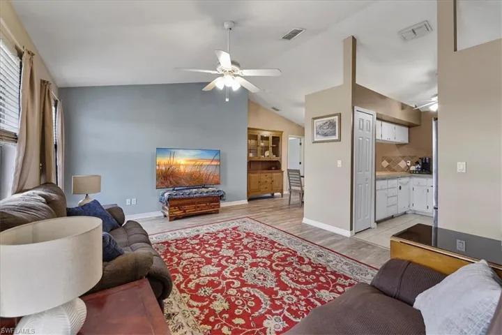 Living room featuring a ceiling fan, lofted ceilingand light wood-style flooring
