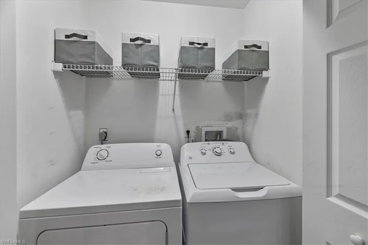 Laundry area with washing machine and clothes dryer and laundry supply shelf