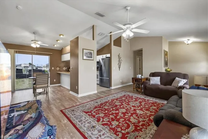 Living room featuring lofted ceiling, light wood-type flooring, and a ceiling fan