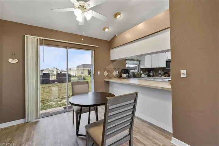 Dining area with baseboards, lofted ceiling, ceiling fan, and light wood-style flooring
