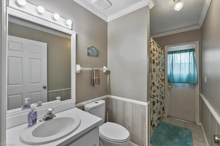 Bathroom with crown molding, toilet, and tile patterned flooring