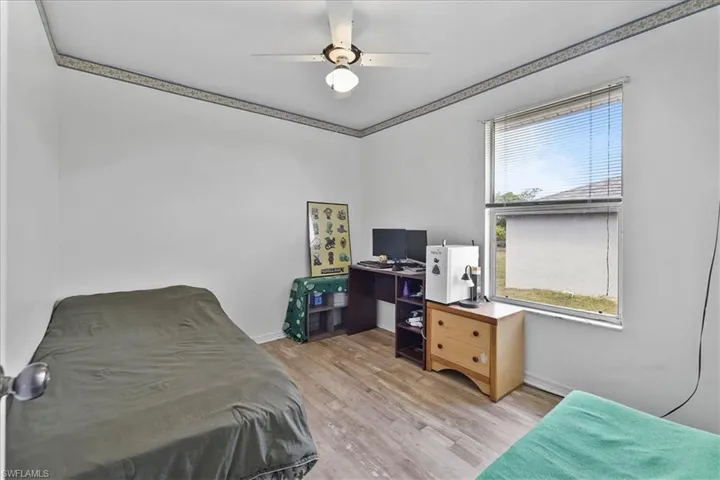 Bedroom featuring a ceiling fan, baseboards, and wood look finished floors