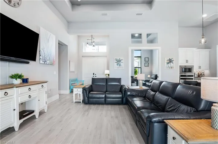 Living area with a towering ceiling, light wood finished floors, baseboards, and visible vents