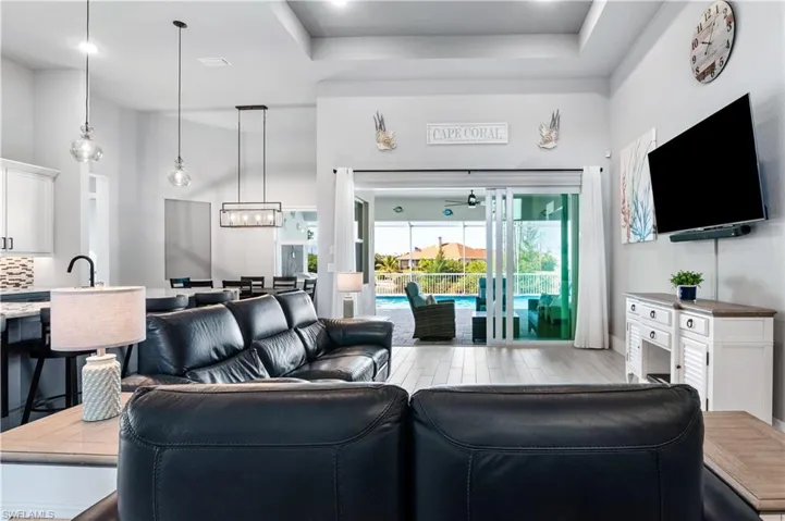 Living area featuring a towering ceiling, light wood finished floors, visible vents, and a raised ceiling