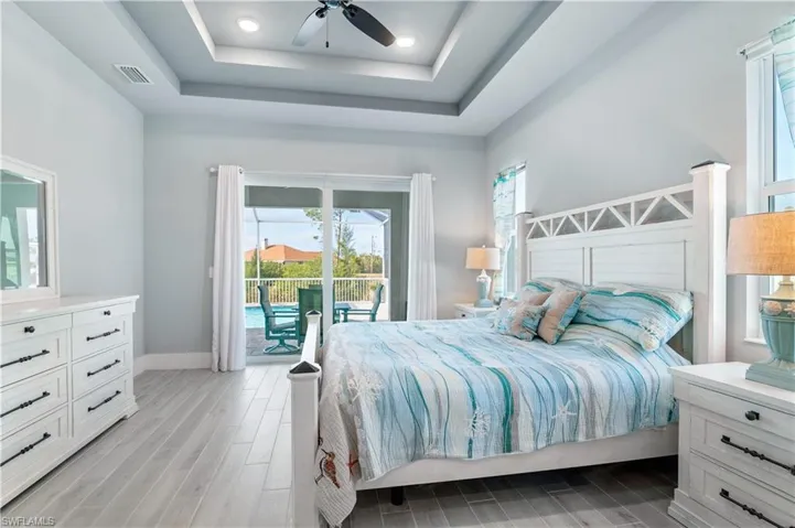 Bedroom with access to outside, visible vents, a tray ceiling, and wood finish floors