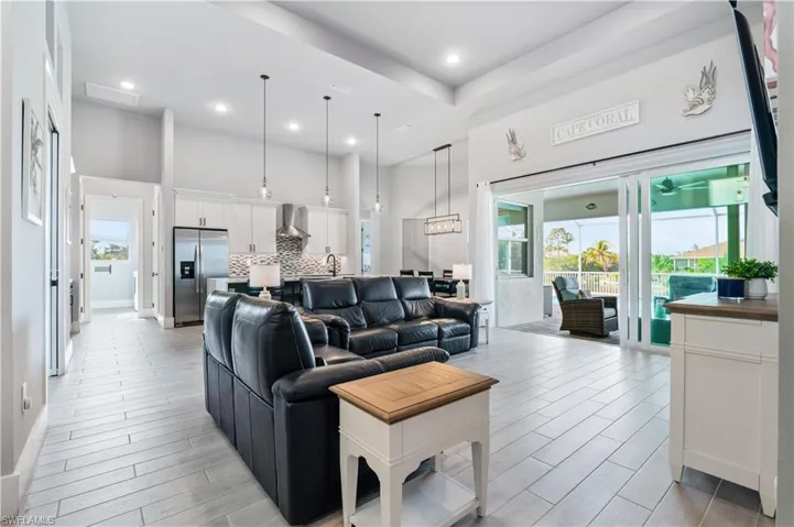 Living area with wood finish floors, a towering ceiling, and recessed lighting