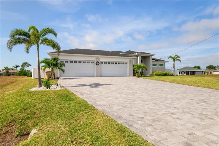 View of front facade with a garage, stucco siding, decorative driveway, and a front yard