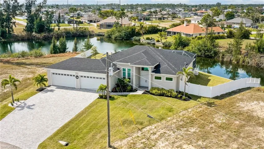 View of front of home with a garage, a water view, fence, decorative driveway, and a residential view