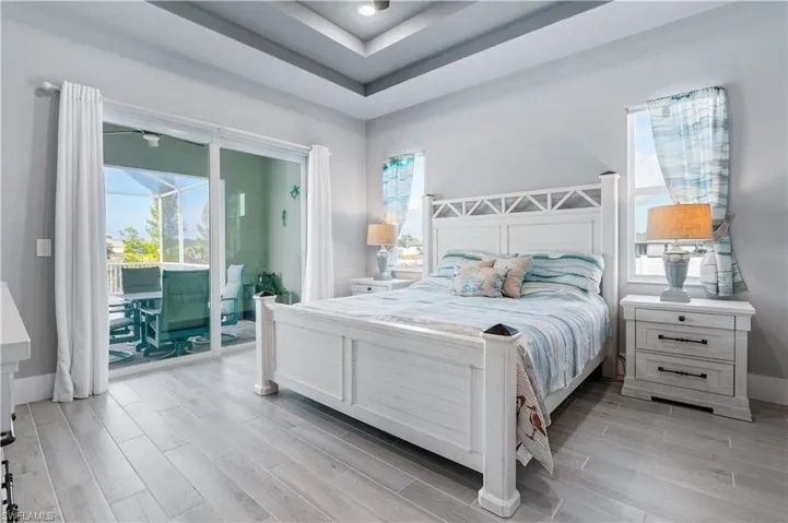 Bedroom featuring access to exterior, wood finish floors, a sunroom, and multiple windows