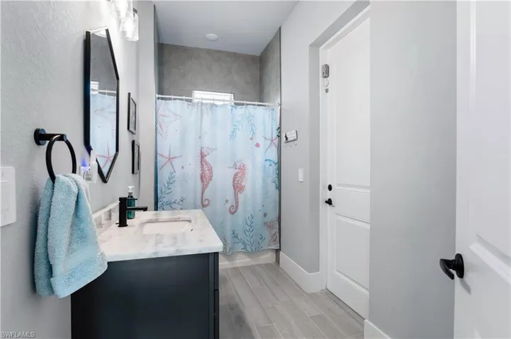 Full bathroom with wood tiled floor, baseboards, and vanity