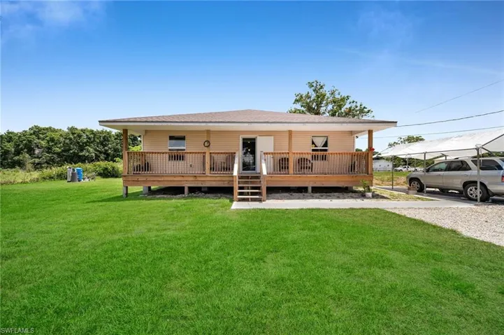Front of property featuring a lawn and a wooden deck