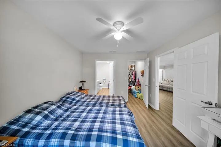 Bedroom with ceiling fan, ensuite bathroom, a closet, and light hardwood / wood-style flooring