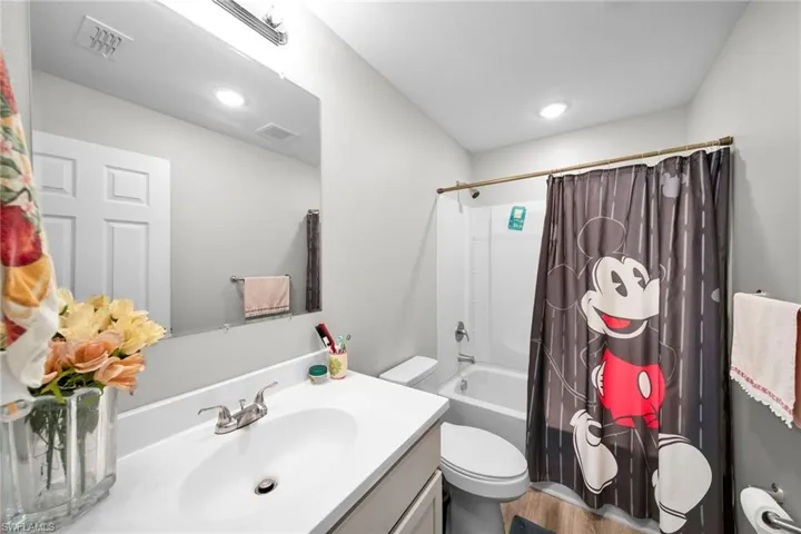 Full bathroom featuring hardwood / wood-style flooring, toilet, vanity, and shower / tub combo with curtain