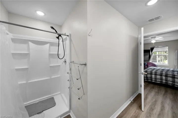 Bathroom with a shower with curtain, ceiling fan, and hardwood / wood-style flooring