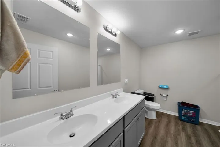 Bathroom with hardwood / wood-style flooring, dual vanity, and toilet