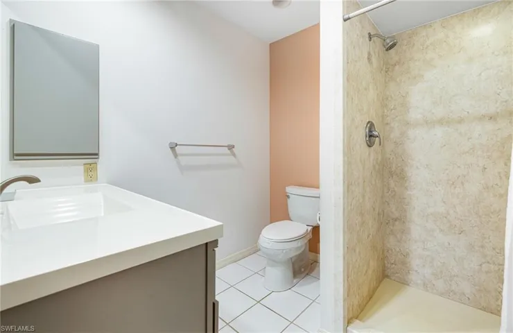 Bathroom featuring tile patterned floors, vanity, toilet, and a tile shower