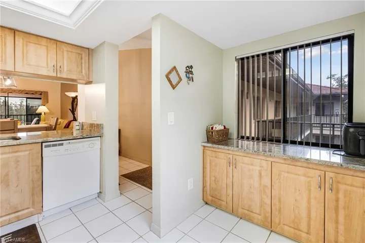 Kitchen featuring light brown cabinetry, white dishwasher, and light tile patterned floors