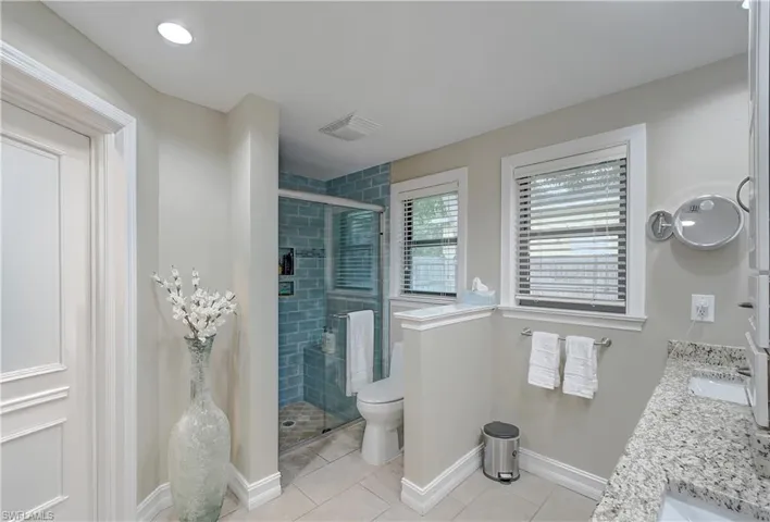 Master Bathroom with dual bowl vanity, an enclosed shower, toilet, and tile floors