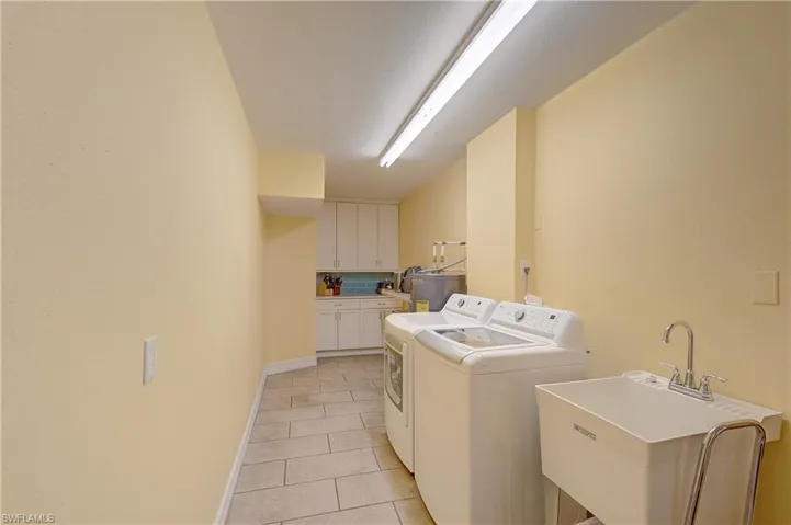 Laundry room with washer and dryer, sink, light tile flooring, and addition cabinets and counter space