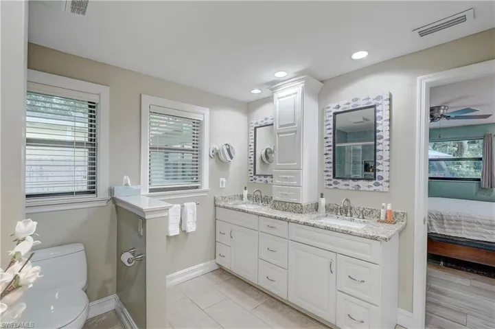 Bathroom featuring double vanity, plenty of natural light, ceiling fan, and toilet