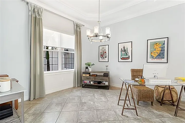 Home office with tile floors, a raised ceiling, crown molding, and a chandelier