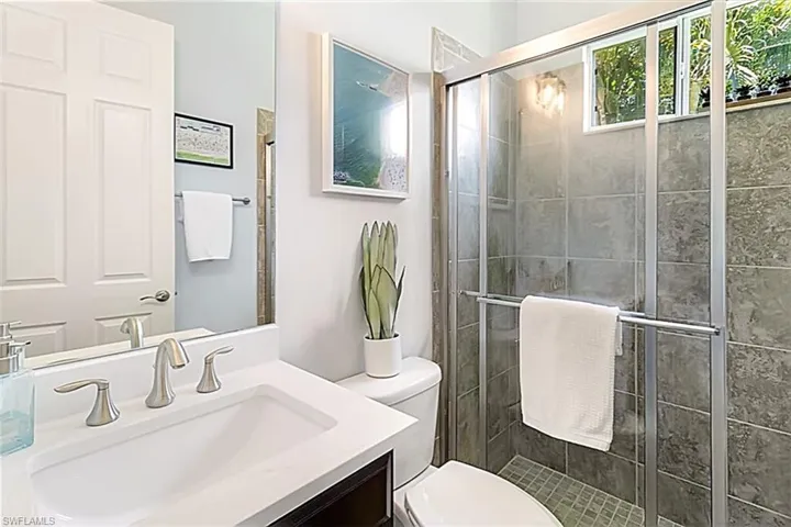 Bathroom featuring a shower with shower door, vanity, and toilet