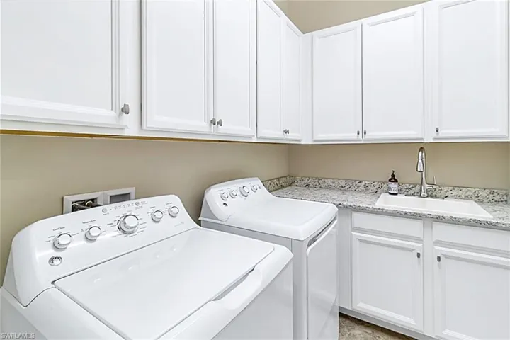 Laundry room featuring cabinets, sink, washer and clothes dryer