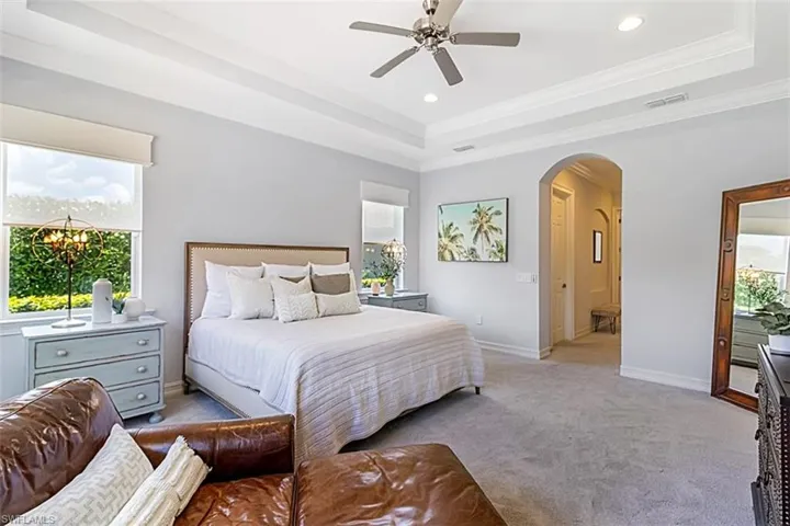 Bedroom featuring Karastan carpet, crown molding, a raised ceiling, and ceiling fan
