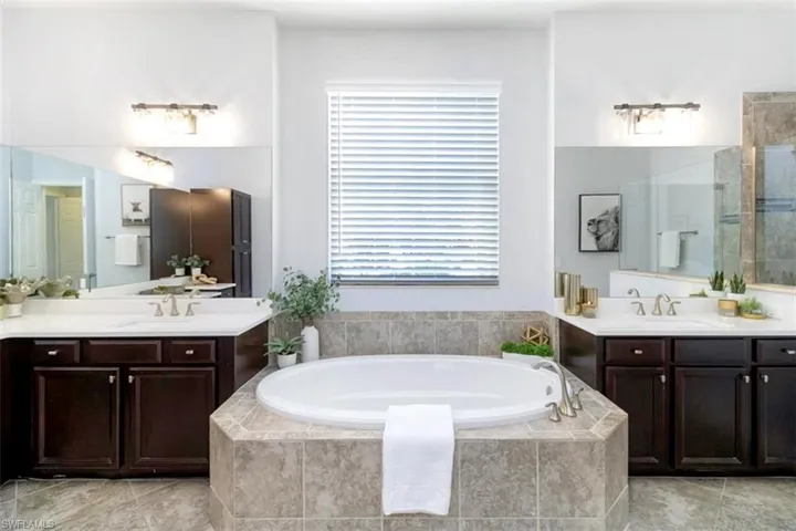 Bathroom featuring tile flooring, dual sinks, tiled bath, and oversized vanities