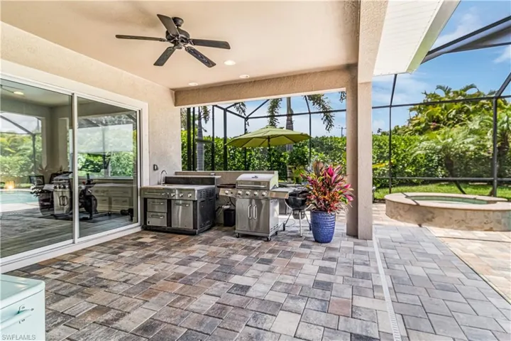 View of patio outdoor kitchen area featuring an in ground spa, screen enclosure
