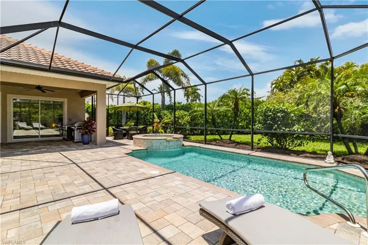 View of swimming pool with a patio, screen enclosure, an in ground spa