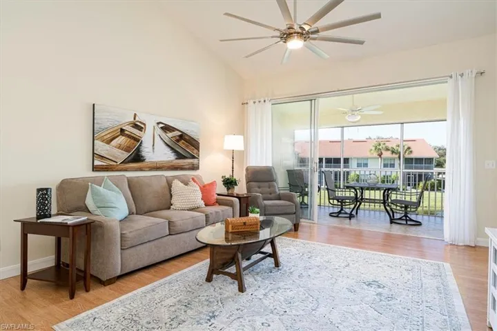 Living room featuring 72" ceiling fan & volume ceiling overlooking balcony water views