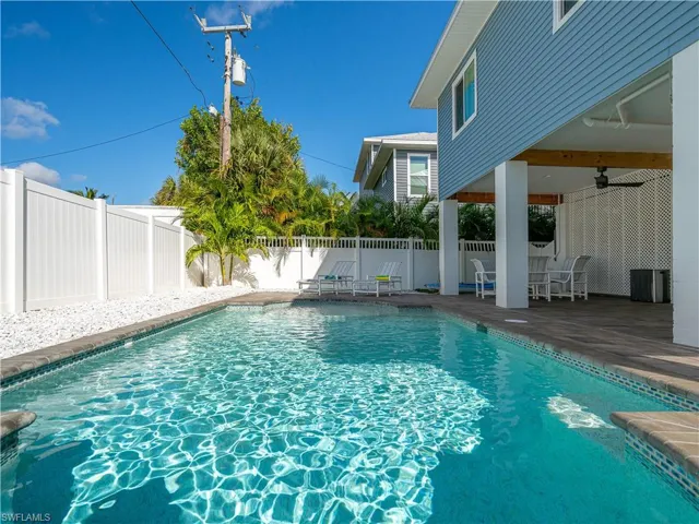 FULL BELOW GROUND CONCRETE POOL SURROUNDED BY PRIVACY FENCE.